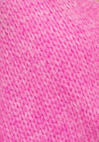 Pletená látka v živé růžové barvě, s texturovaným vzorem měkkých vláken. Povrch je mírně chlupatý s různými odstíny růžové.