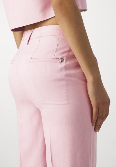 Pantalons rose ajustés avec un motif à rayures, présentant des poches arrière et un accent métallique près de la poche. Texture lisse.