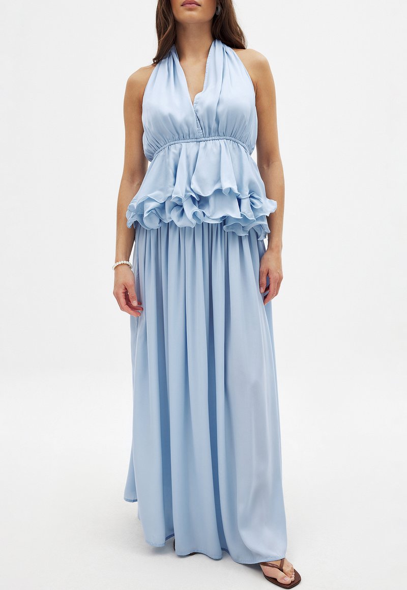 Robe maxi halter bleu clair avec détail en peplum froncé, tissu fluide et taille froncée. Design minimaliste avec texture lisse.