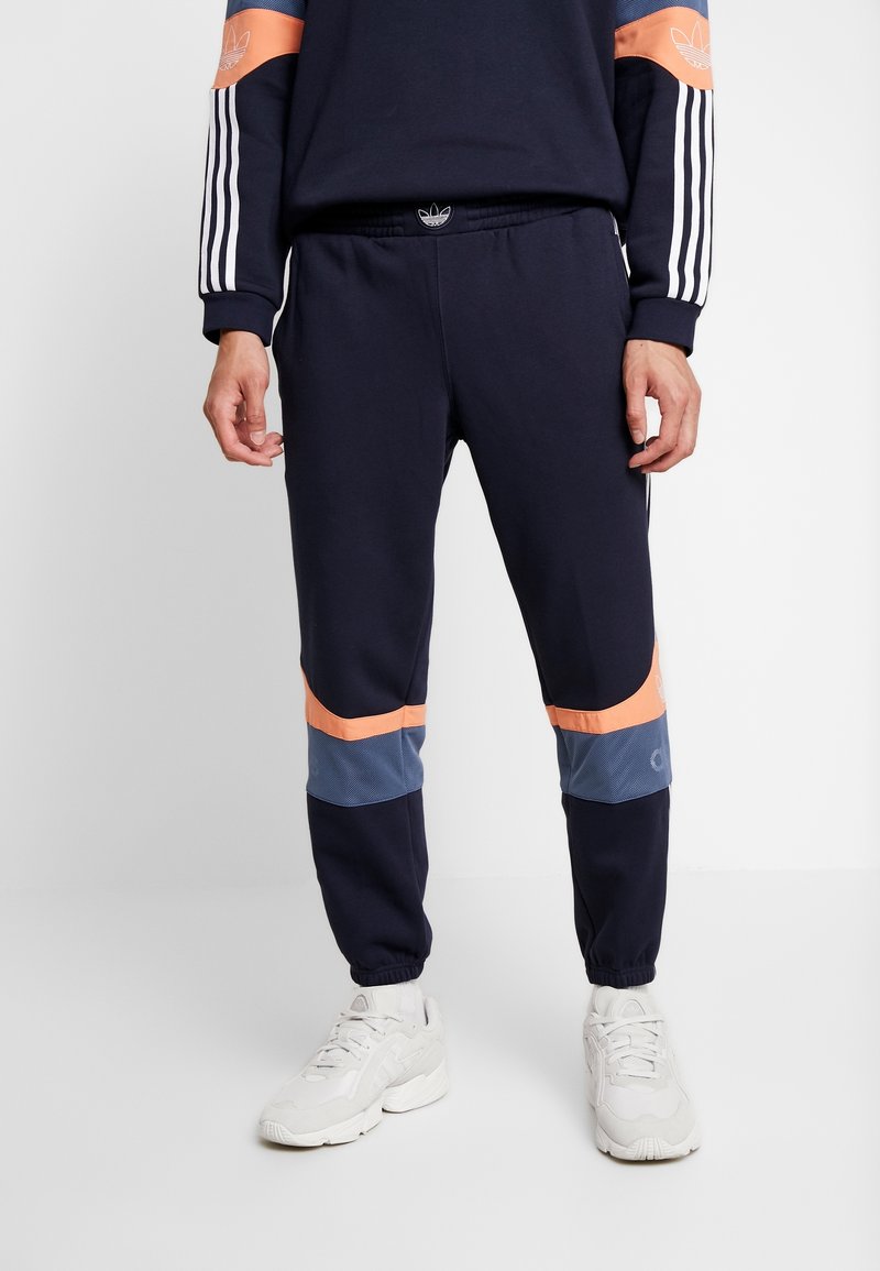 Marina joggers med ljusorange och blå meshpaneler. Har en elastisk midja och ribbade muddar. Tillverkade av mjukt, andningsbart material.