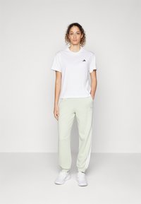 adidas Sportswear ESSENTIALS 3-STRIPES LOOSE-FIT - Tepláky - linen green