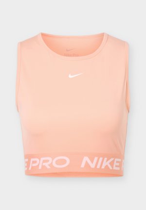 Őszibarack színű Nike Pro sportos crop top ujjatlan kialakítással, kerek nyakkivágással, fehér Nike swoosh logóval elöl középen, és márkázott elasztikus szegéllyel.