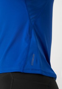 Blue athletic shirt made of lightweight, moisture-wicking fabric, featuring a smooth texture and a small "AEROREADY" logo on the side seam.