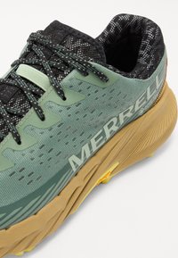Green trail shoes with a textured mesh upper, reinforced accents, and a chunky gum rubber sole. Features "MERRELL" branding in white.