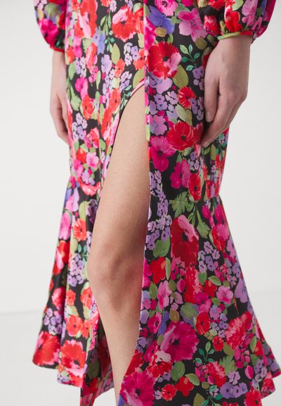 Abito floreale di colore nero con grandi rose rosa, rosse e viola. Presenta una scollatura alta fino alla coscia e maniche arricciate per un tocco di texture in più.