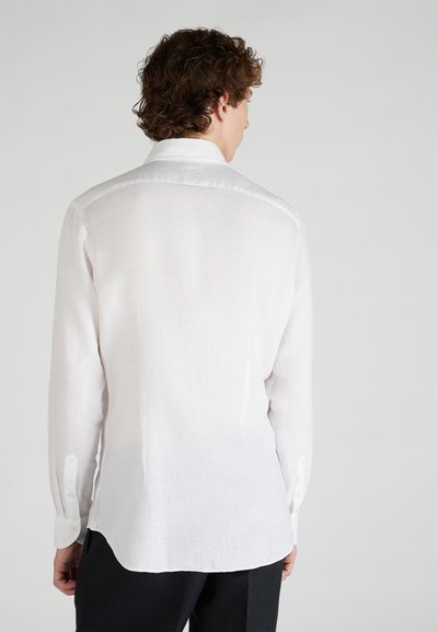 White linen shirt with long sleeves, button cuffs, and a slightly curved hem. Smooth texture, tailored fit, and standard collar design.