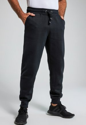 Pantalones de chándal negros con cintura elástica y cordón, con bolsillos laterales y piernas ajustadas. La tela parece suave y texturizada.