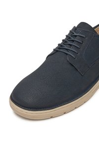Granatowe buty sznurowane z teksturowanym wierzchem, okrągłym noskiem i beżową gumową podeszwą z delikatnym wzorem antypoślizgowym.