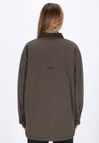 Giacca oversize verde oliva con colletto in corduroy, polsini con bottoni a pressione e dettaglio con pattina sul retro. Tessuto liscio e con texture.