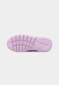 Semelle d'une chaussure Nike violette avec des rainures flexibles et un motif tacheté sur un fond uni clair.