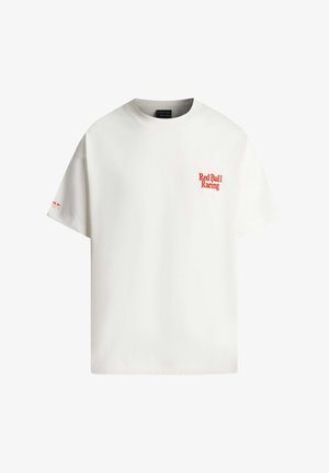 Bela majica s kratkimi rokavi s rdečim napisom »Red Bull Racing« na levi prsi in majhnim logotipom Red Bull na levem rokavu.