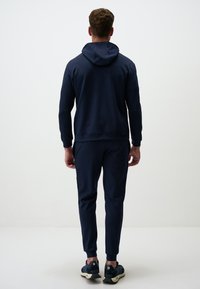 Completo sportivo blu navy con top con cappuccio e pantaloni coordinati. Caratterizzato da una vestibilità comoda e polsini a coste, è realizzato con elementi di design minimalisti.