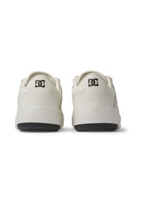 DC tenisky, off-white kožený zvršok, polstrovaný golier, dvojfarebná podrážka s čiernym dnom, logo na päte, hladká textúra, voľnočasový dizajn.