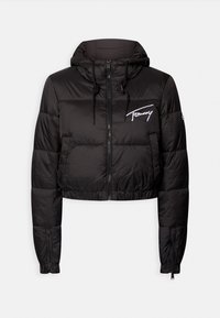 Černá zkrácená péřová bunda s kapucí, která má elastické manžety, přední zip a bílé vyšívané logo na levém hrudníku. Hladká textura.