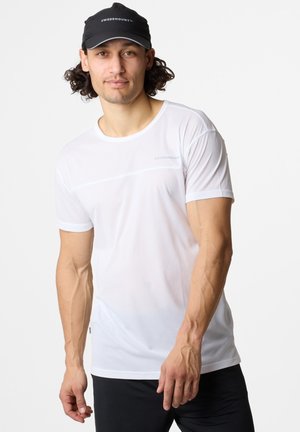 Valkoinen urheilupaita, jossa on teksturoitu verkkokangas, pyöreä kaula-aukko, lyhyet hihat ja hillitty logoyksityiskohta. Yhdistetty mustiin urheiluhousuihin.