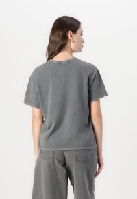 Gray oversized T-shirt in soft cotton, featuring short sleeves and a crew neckline. Faded texture with a relaxed fit.