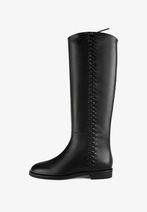 Tall black leather boot with a rounded toe, flat sole, and decorative lacing detail along the back. Smooth texture and minimal design.