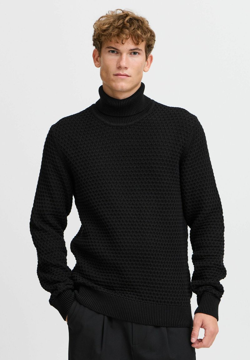 Jersey de punto negro con cuello alto, con un patrón texturizado, puños y dobladillo acanalados. Hecho de una tela suave, presenta un diseño de ajuste holgado.