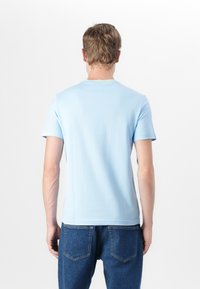 T-shirt bleu clair à manches courtes en tissu doux, avec col rond et coupe régulière, associé à un jean en denim bleu.