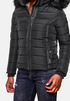 Schwarze gepolsterte Jacke mit abnehmbarem Kunstpelzkragen, Reißverschluss und Druckknopfverschlüssen, seitlichen Taschen und gerippten Bündchen. Getragen über dunklen Jeans.