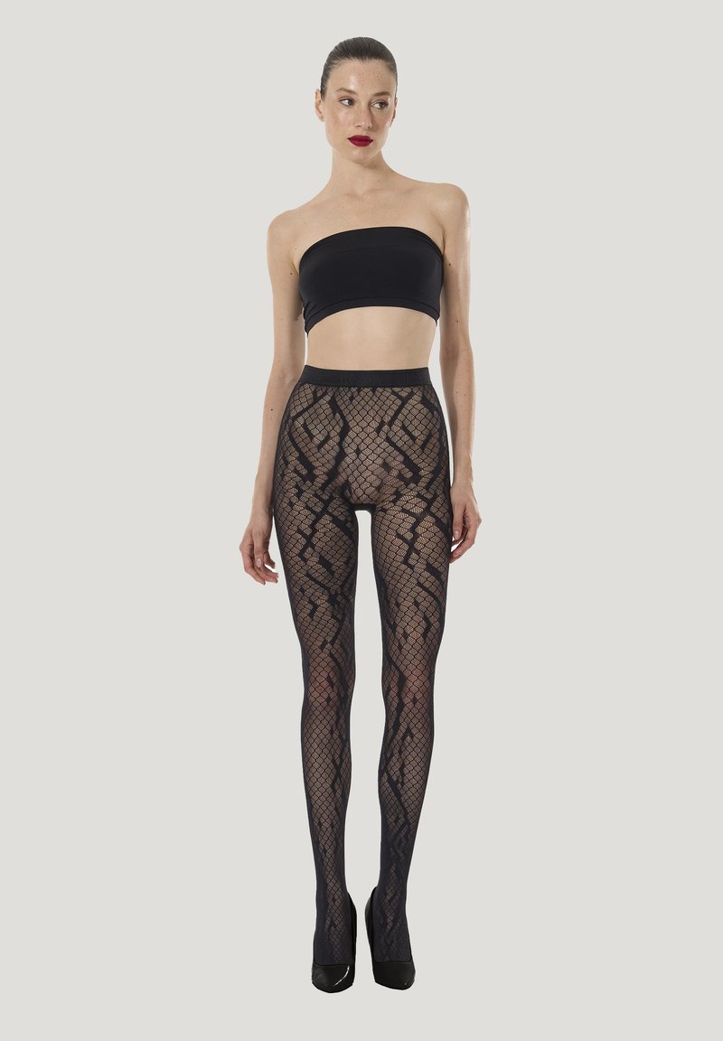 Durchsichtige schwarze Netzstrumpfhosen mit geometrischen Mustern, hohem Bund und glattem Finish, kombiniert mit einem schwarzen Crop-Top und hohen Absätzen.