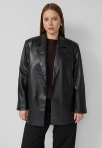 Blazer in pelle nera con chiusura a bottone singolo, rever pronunciati, tasche laterali e una vestibilità leggermente oversize. Texture liscia.