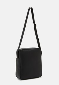 Sac messager noir en matériau durable, de forme rectangulaire, avec une bandoulière réglable et une texture lisse dotée d'une fermeture éclair.