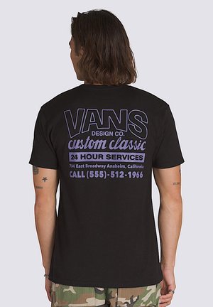 Camiseta de algodón negra con gran texto blanco y morado en la parte posterior, con un logo y detalles de contacto. Diseño de mangas cortas y cuello redondo.
