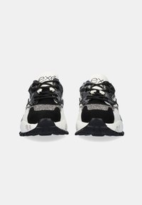 Par de zapatillas deportivas en negro, blanco y gris con tela de lentejuelas, cordones negros y suelas gruesas negras, vistas desde el frente.