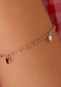 Zilveren kettingarmband met een kleine hartjescharme, met een zachte textuur en een delicate, minimalistische stijl.