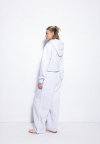 Hellgrauer Sweatshirt und passende weite Hose aus weichem Stoff. Mit Kapuze, lockerer Passform und elastischem Bund.