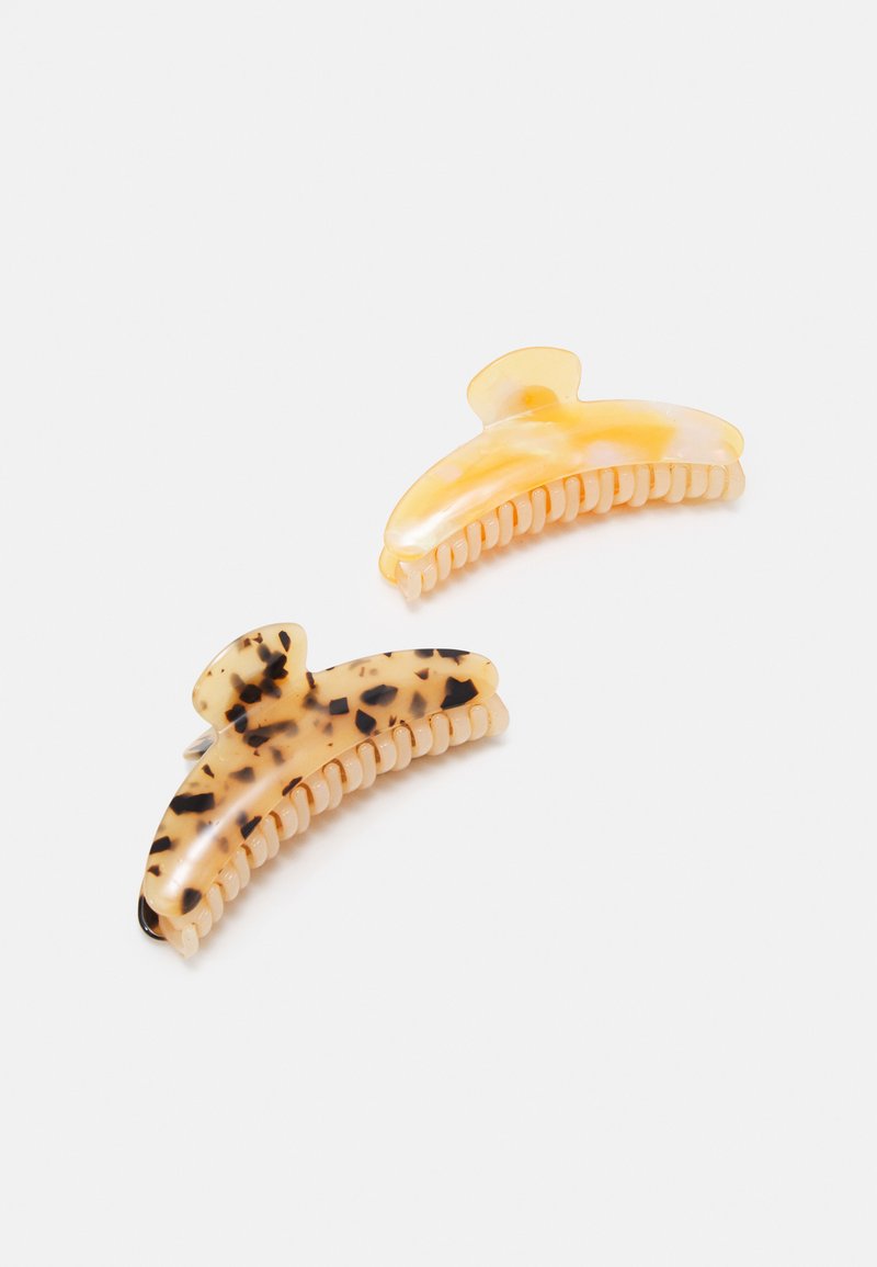 Two hair clips made of plastic, one in solid light yellow and the other in a tortoiseshell pattern, featuring teeth for secure grip.
