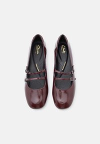 Burgundowe lakierowane buty Mary Jane z płaską podeszwą, z dwoma regulowanymi paskami i zamkniętym, okrągłym noskiem.