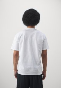 Witte katoenen t-shirt met korte mouwen en een ronde hals, gezien vanaf de achterkant. Glad textuur, relaxte pasvorm, minimalistisch ontwerp.