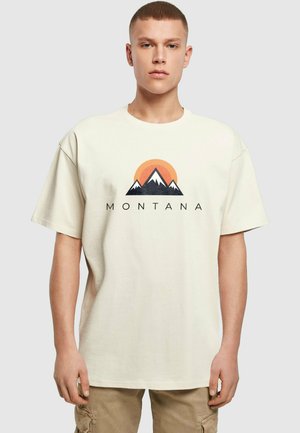 Cremefarvet bomulds T-shirt med et bjergmotiv i sort og orange samt teksten "MONTANA" nedenunder. Afslappet pasform og rund halsudskæring.
