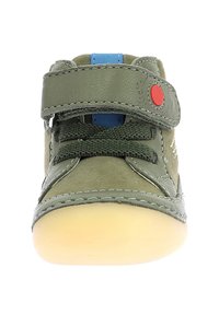 Zapatilla alta de cuero verde con una correa ancha, acento azul, cordones negros y puntera redonda. Presenta una suela de goma beige y detalles cosidos.