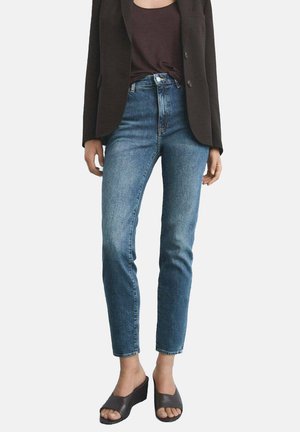 Hoch taillierte Jeans aus blauen Denim mit Slim Fit, ausgestattet mit fünf Taschen und einem Knopfverschluss, kombiniert mit einem schwarzen Blazer und offenen Wedgesandalen.
