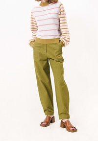 Pruhovaný svetr v pastelových barvách, spárovaný s olivově zelenými širokými kalhotami a hnědými sandály na blokovém podpatku. Texturovaná pletenina a přizpůsobený střih.