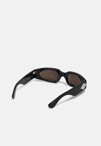 Ochelari de soare negri cu un finisaj lucios, având lentile maronii și un accent geometric argintiu pe lateral. Design elegant și unghiular.
