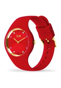 Orologio da polso in silicone rosso con un quadrante rotondo accentato in oro. Presenta lancette delle ore e dei minuti in oro e pietre decorative attorno al quadrante.