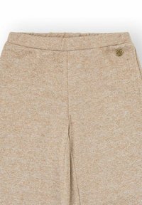 Pantalones de chándal beige hechos de una tela texturizada con una cinturilla elástica y un pequeño logotipo redondo cerca de la cintura.