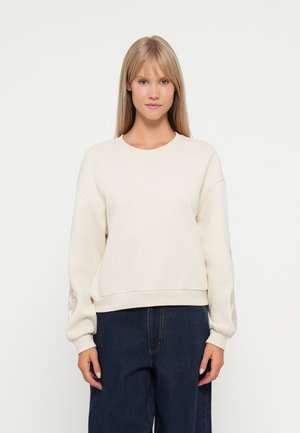 Hellbeige Sweatshirt mit rundem Halsausschnitt und langen, puffigen Ärmeln. Besitzt dekorative Stickereien an den Ärmeln und eine lockere Passform.