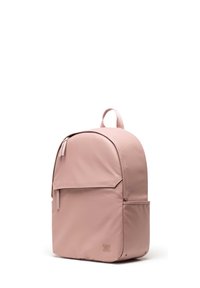 Ružičasti ruksak za leđa zaobljenog oblika, izrađen od glatkog materijala. Ima prednji džep, vertikalne zatvarače i ručku na vrhu. Minimalistički dizajn.