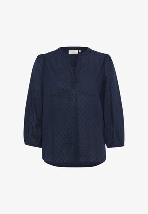 Modra bluzica s V-izrezom, nabranimi rokavi in teksturiranim vzorcem pik. Lahka tkanina z ohlapnim krojem in ukrivljenim robom.