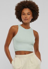 Light blue cropped tank top made of ribbed fabric, featuring a rounded neckline and sleeveless design, paired with light-colored sweatpants.