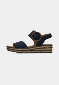 Navy blue suede sandal with a wide strap, circular wooden accent, and a stacked, textured midsole in light brown and dark gray tones.