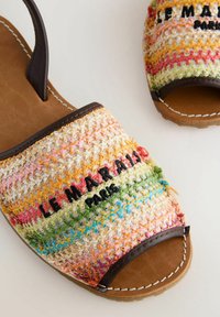 Sandales à bout ouvert avec des brides tissées multicolores, garniture en cuir marron et "MARRAKESH" brodé en noir sur la bride avant.