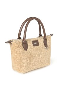 Bolso de mano de color beige y peludo, con asas y detalles de cuero marrón oscuro, forma rectangular y un pequeño logotipo en parche en la parte frontal.