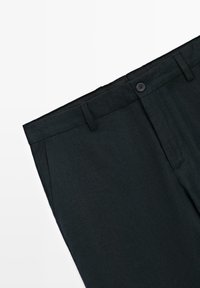 Pantaloni neri su misura con passanti per cintura, tasche laterali e chiusura con bottone su sfondo bianco.
