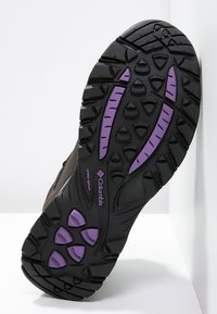 Černá a fialová robustní podrážka turistické obuvi s hlubokými drážkami a viditelným logem Columbia Omni-Grip.